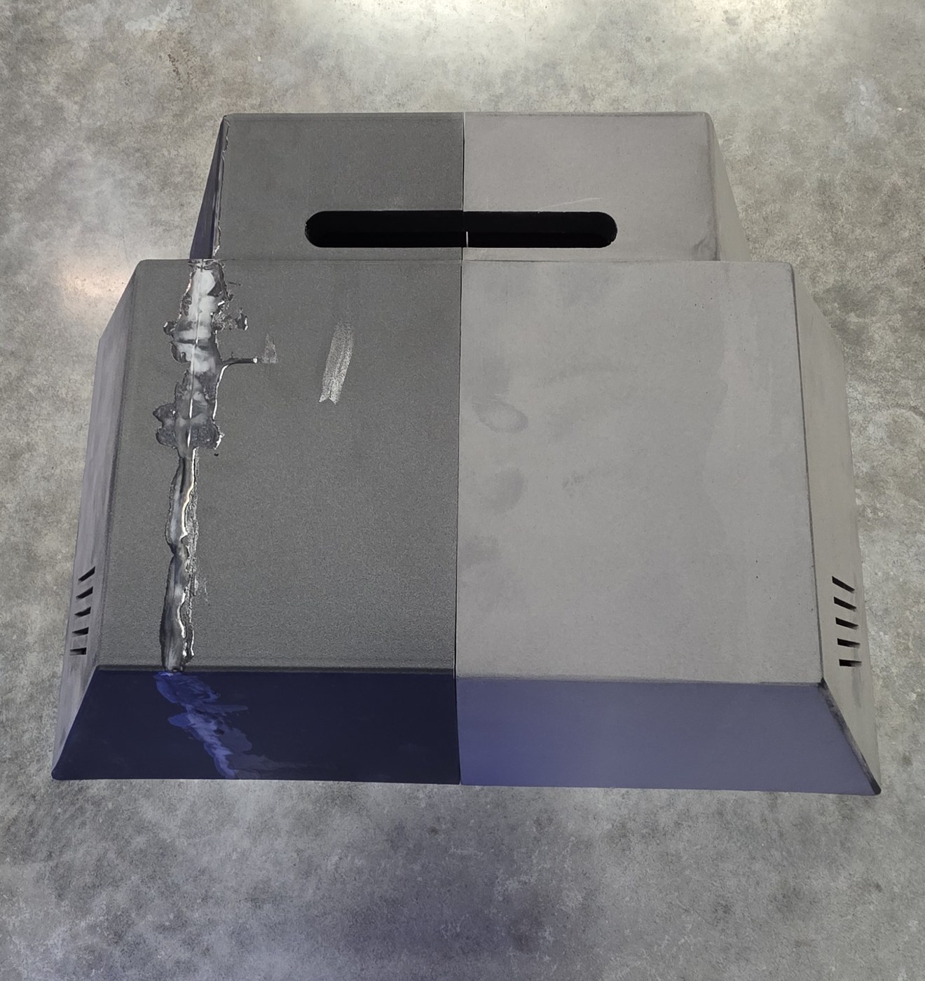 Two matching printed housings on the floor, the left one with a raw glue seam still clearly visible, the right one sanded smooth so the seam has almost disappeared